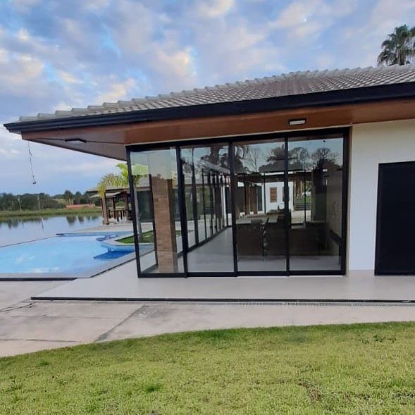 Área gourmet com portas de vidro de correr e piscina à beira de um lago