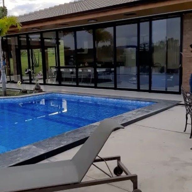 Casa com piscina e panos de vidro com esquadria preta do piso ao teto