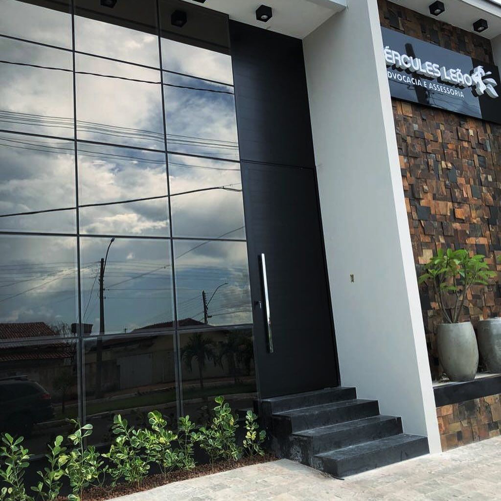 Fachada comercial em pele de vidro com porta pivotante preta