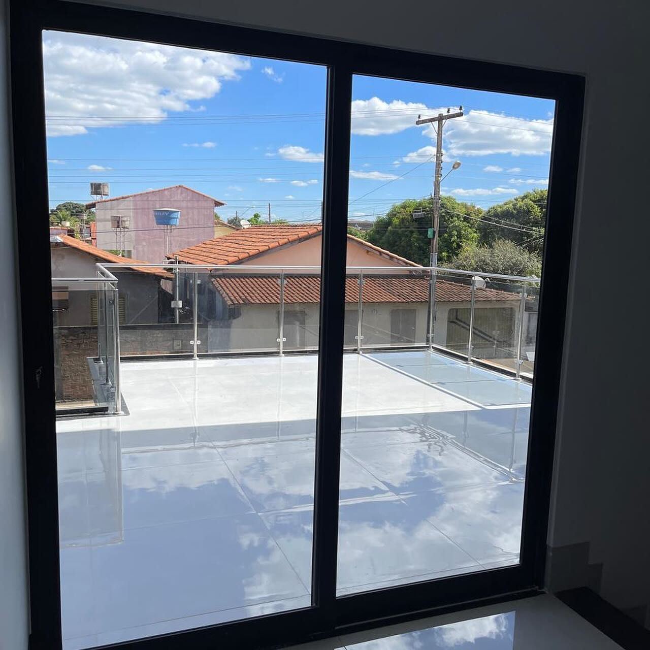 Porta de correr preta abrindo para terraço com guarda-corpo de vidro