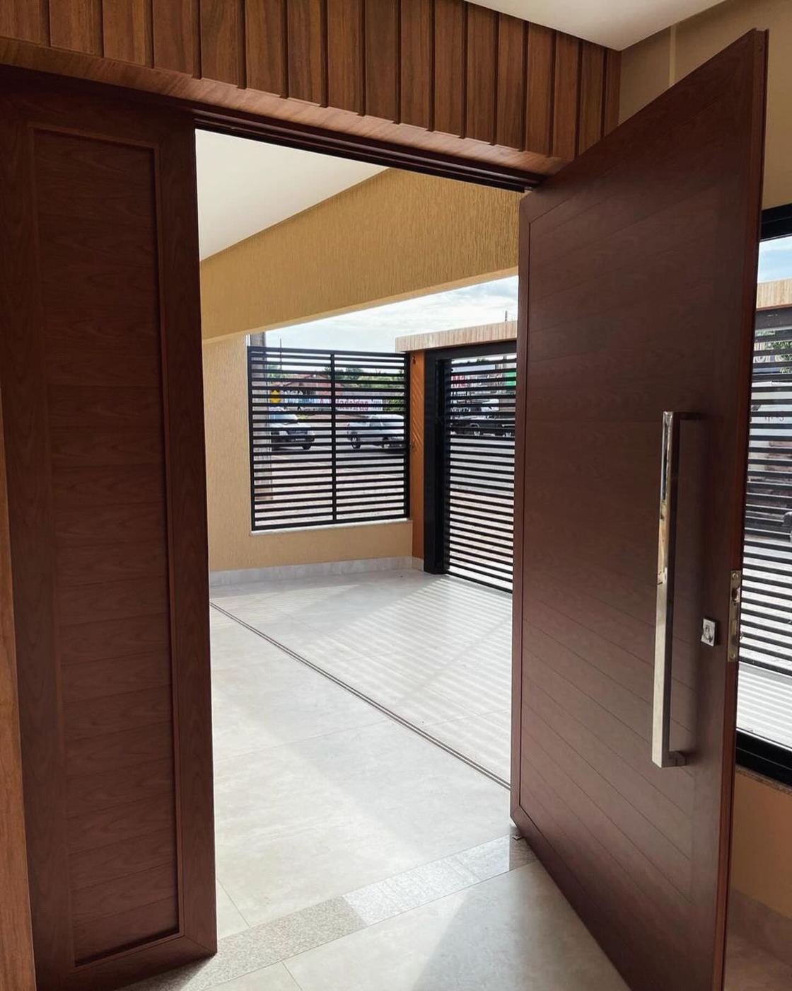 Porta pivotante madeirada aberta em entrada de casa