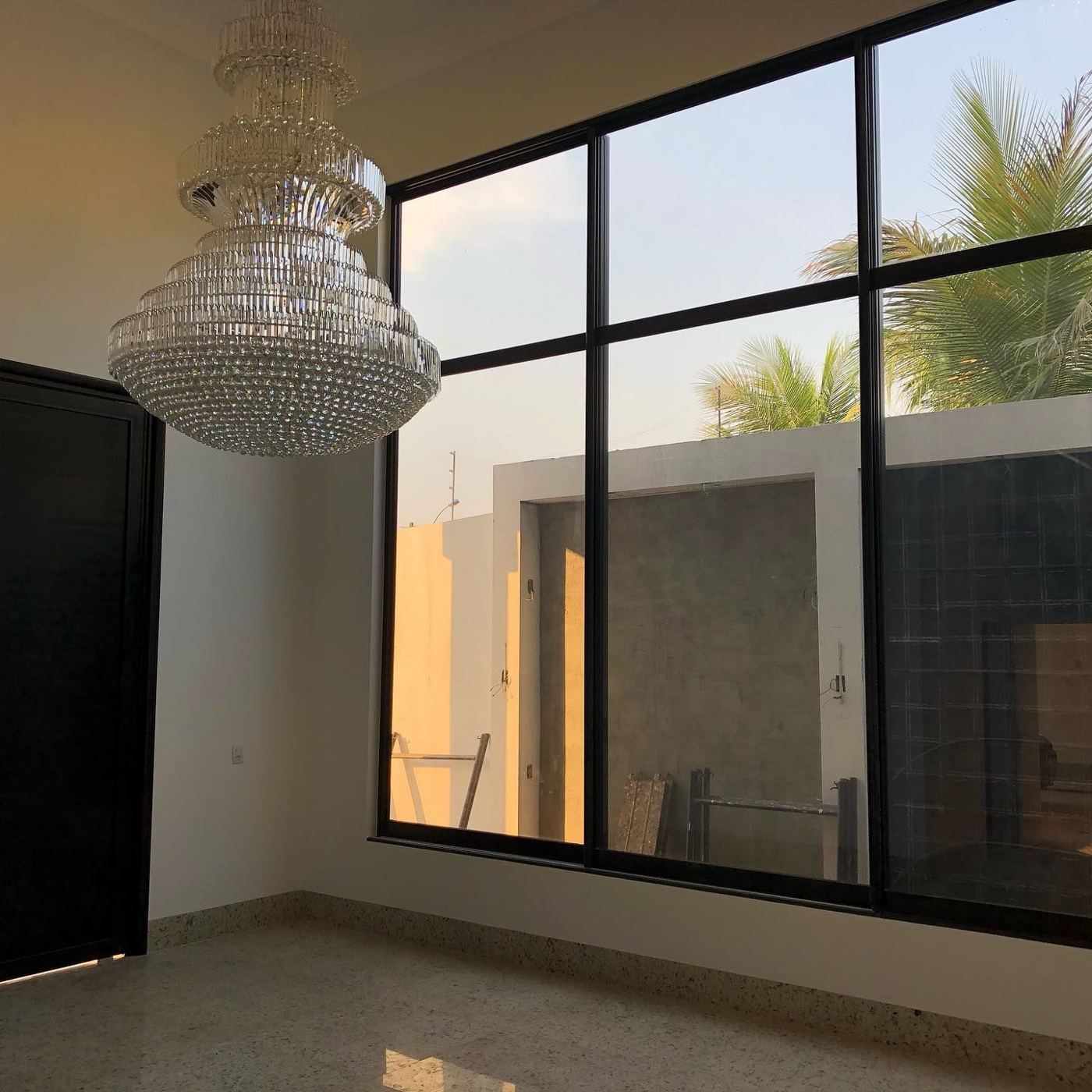 Sala de pé-direito duplo com esquadria preta e lustre